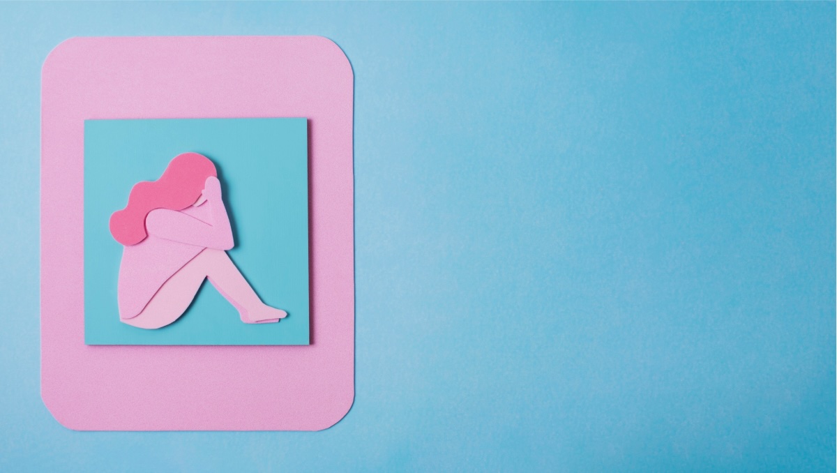 Paper-cut illustration of a woman sitting with her knees drawn up
